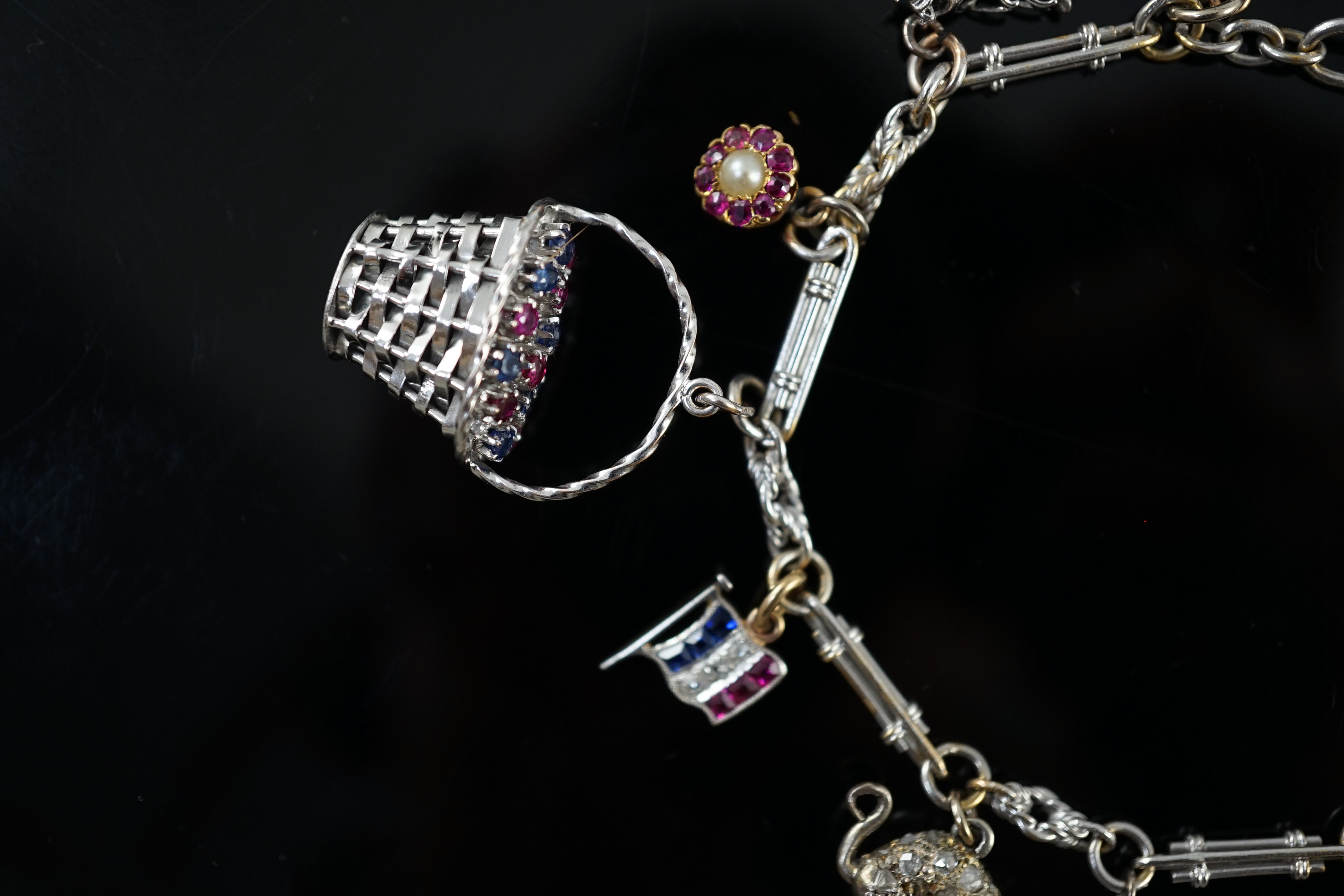 A French 18ct white gold circular and baton link charm bracelet, hung with eleven assorted charms